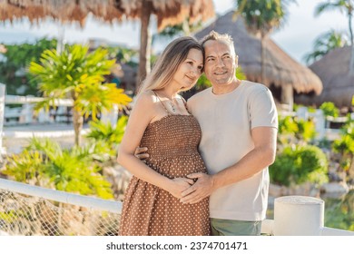 A happy, mature couple over 40, enjoying a leisurely walk in a park, their joy evident as they embrace the journey of pregnancy later in life - Shutterstock ID 2374701471