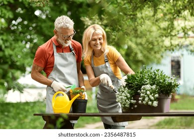 Happy Mature Couple Planting Flowers Together Outdoors In Garden, Smiling Romantic Senior Spouses Wearing Aprons Enjoying Gardening, Managing Potted Plants On Backyard, Having Fun Outside - Powered by Shutterstock