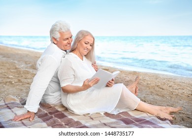 Happy mature couple reading book at sea resort - Shutterstock ID 1448735177