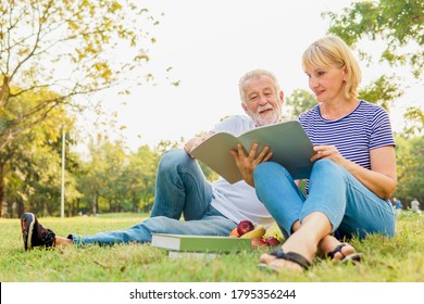 Happy Mature couple reading the book together and having picnic in the garden at the summer day. Retirement, Picnic, Relax, Older, Lover and dating concept. 