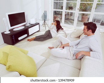 Happy Mature Couple Sitting On Couch And Watching Television Together