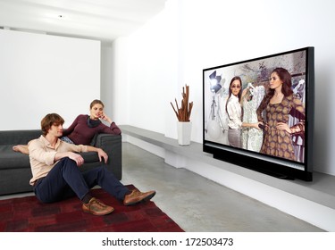 Happy Mature Couple Sitting On Couch And Watching Television Together