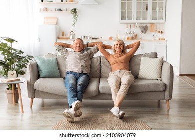 Happy Mature Couple Sitting On Couch Relaxing And Resting At Home, Holding Hands Behind Head, Enjoying Comfort Of Their House. Relaxed Senior Spouses Having Lazy Weekend Indoors. Full Length - Powered by Shutterstock