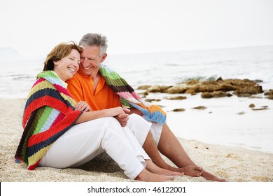 Happy mature couple sitting on the beach.