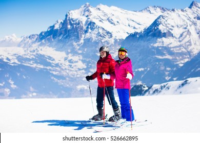 Happy Mature Couple Skiing In The Alps Mountains. Senior Man And Woman Enjoying Ski Vacation In Alpine Resort. Active Retirement. Healthy Winter Sport For Every Age.