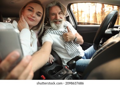 Happy Mature Couple Taking Selfie In Car