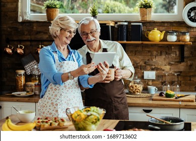 Happy mature couple using digital tablet while preparing food in the kitchen.  - Powered by Shutterstock