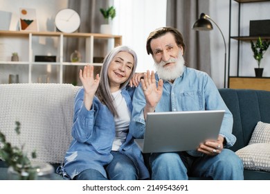 Happy Mature Couple Using Laptop Watching Movie Together Sitting On Couch At Home. Older Couple Browsing Internet On Computer Reading Online News On Weekend. Technology And Gadgets