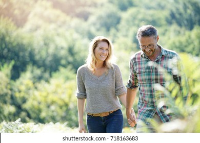 Happy Mature Couple Walking In Countryside On Sunny Day