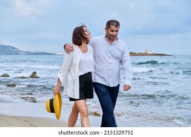 Happy mature couple walking on the beach - Shutterstock ID 2151329751