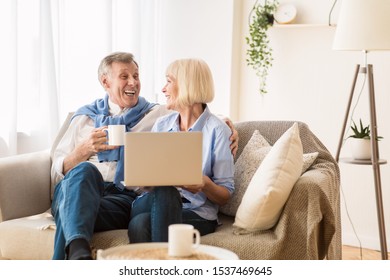 Happy Mature Couple Watching Comedy Film On Laptop, Man Drinking Tea, Free Space