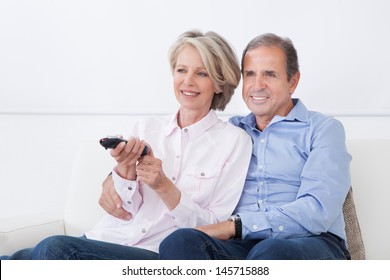 Happy Mature Couple Watching Television At Home