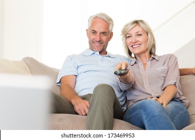 Happy Mature Couple Watching Tv On Sofa At Home