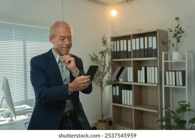 Happy mature executive manager holding mobile phone, reading message with good news, using business mobile apps, browsing internet, checking corporate email in modern office - Powered by Shutterstock