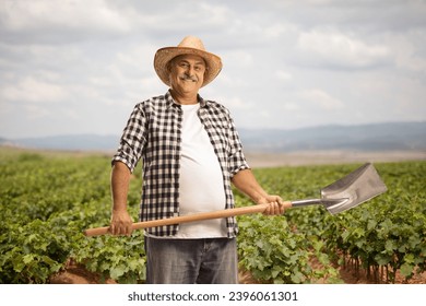 Happy mature farmer with a spade standing on a grapevine field - Powered by Shutterstock