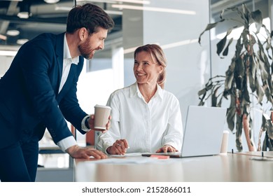 Happy Mature Female Boss Discussing Project With Employee That Showing Presentation 