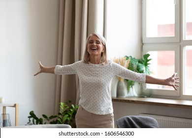 Happy mature female pensioner stand with arms open feel positive excited welcoming new good day, smiling senior middle-aged woman have fun satisfied with life, enjoy weekend leisure time