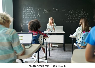 Happy mature female teacher teaching multiethnic kids at maths class in junior middle elementary education school. Diverse children students and teacher interacting at lesson in modern classroom. - Powered by Shutterstock