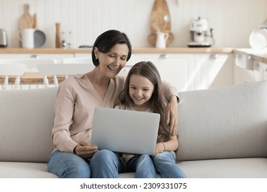 Happy mature grandma and cute little grand child girl using laptop computer at home, enjoying Internet communication, domestic modern technology, watching movie, talking on video call - Powered by Shutterstock