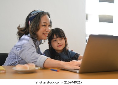 Happy Mature Grandma And Little Grandchild Using Laptop Computer At Home Together. Multi Generational, Family And Love Concept