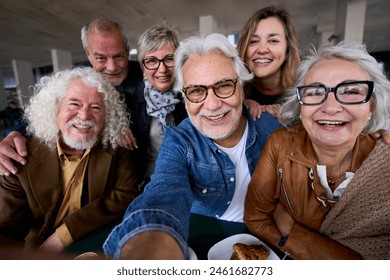 Happy mature gray hair man taking selfie of group seniors Caucasian cheerful friends posing together sitting at cafeteria. Older people looking smiling at camera with snacks on table nursing home  - Powered by Shutterstock