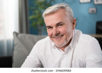 Happy Mature Gray-haired 60s Man Smiling Face White Healthy Teeth Dental Smile Sit On Sofa. Relaxed Old Retired Single Grandfather Posing Alone At Home Look At Camera, Close Up Portrait.