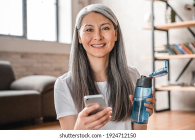 Happy Mature Grey-haired Woman Using Mobile Phone While Training At Home