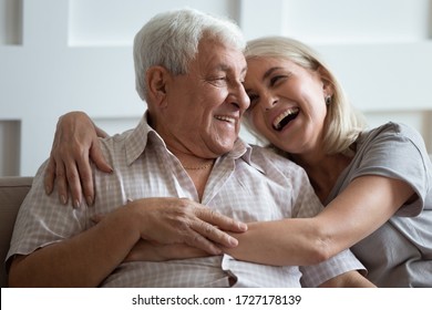 Happy mature husband and wife sit rest on couch at home hugging and cuddling, show care affection, smiling senior loving couple relax on sofa have fun, enjoy tender romantic family weekend together - Powered by Shutterstock