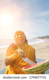 Happy Mature Indian Woman Cutting Watermelon At Vagator Beach