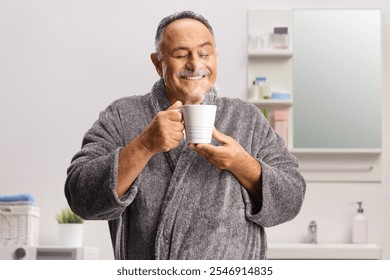 Happy mature man in a bathrobe enjoying a cup of hot steamy drink at home - Powered by Shutterstock