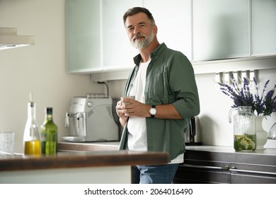 Happy mature man drinking coffee at home in the kitchen, enjoying hot drink in the morning on weekend - Powered by Shutterstock