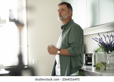 Happy mature man drinking coffee at home in the kitchen, enjoying hot drink in the morning on weekend - Powered by Shutterstock