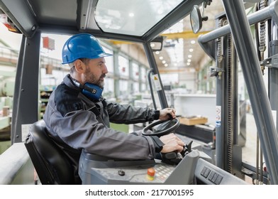 Happy Mature Man Fork Lift Truck Driver Lifting Pallet In Storage Warehouse .