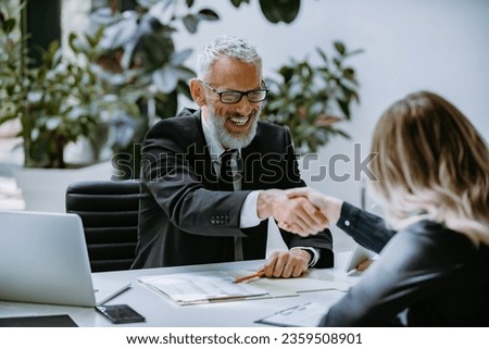 Happy mature man in formalwear shaking hand to successful job candidate in the modern office
