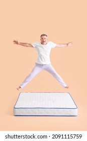 Happy mature man jumping on mattress against color background