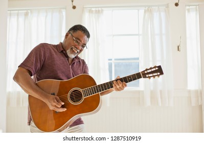 Happy Mature Man Playing An Acoustic Guitar.