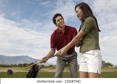 Happy Mature Man Teaching Woman To Play Golf