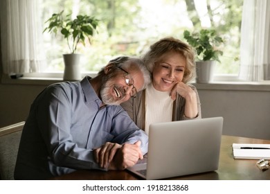 Happy Mature Man And Woman Hugging, Looking At Laptop Screen, Smiling Elderly Couple Cuddling, Watching Movie Or Making Video Call To Relatives, Chatting Online, Enjoying Leisure Time With Gadget