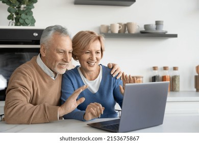 Happy mature married couple making video call on modern laptop, waving hand on webcam, talking online with family, friends or relatives, looking at computer display. Telecommunication concept - Powered by Shutterstock