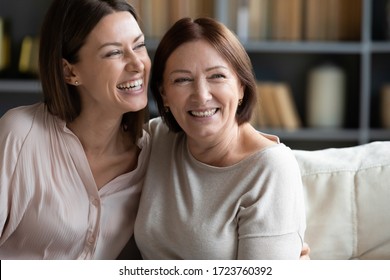 Happy Mature Mother And Adult Daughter Hugging Close Up, Having Fun, Sitting On Couch At Home, Smiling Woman Embracing Older Mum, Spending Leisure Time Together, Two Generations Good Relationship