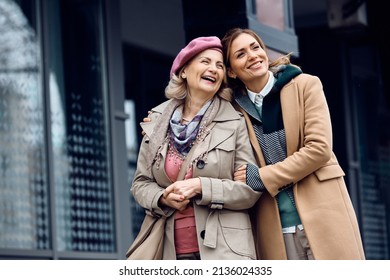 Happy mature mother and her adult daughter enjoying in time together while walking down the street.