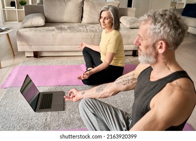 Happy Mature Old Family Couple Meditating Together At Home With Laptop. Fit Healthy Senior Mid Age Man And Woman Doing Yoga Exercise Watching Digital Online Virtual Class, Feeling No Stress Free.