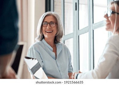 Happy Mature Old Female Mentor Coach Supervisor Training Young Interns At Group Office Meeting Professional Workshop. Smiling Middle Aged Teacher Professor Laughing With Students At University Class