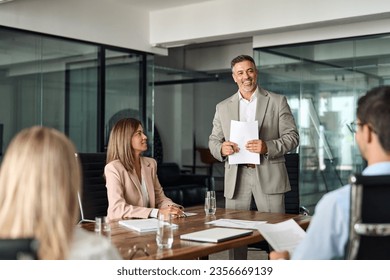 Happy mature older Latin business man team manager CEO executive leading group corporate meeting in board room. Diverse business team people company staff working together at office table. - Powered by Shutterstock