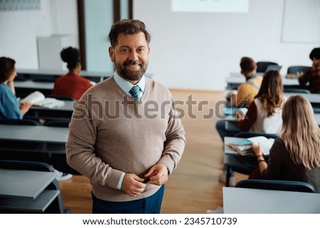 Happy mature professor in lecture hall looking at camera. his student are learning int he background.