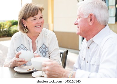 Happy Mature Senior Couple Reading A Newspaper Outside At A Cafe