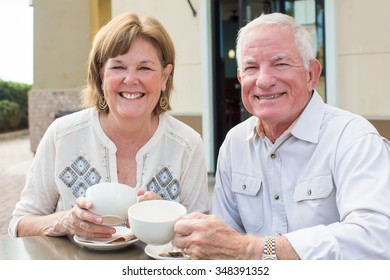 Happy Mature Senior Couple Reading A Newspaper Outside At A Cafe