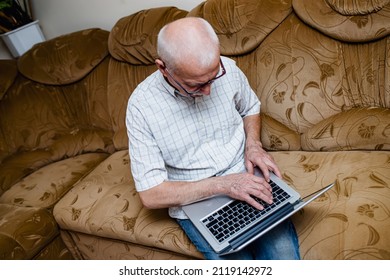 Happy Mature Senior Man In His 60s, Having Fun Studying Online. The Concept Of Older Technologies. Old Man Working Remotely From Home On Laptop. Top View