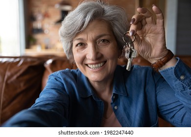 Happy mature smiling woman holding camera showing bunch of keys from new own house, close up. Bank loan for older citizen, real-estate agent female portrait, vacation retreat commercial offer concept - Powered by Shutterstock