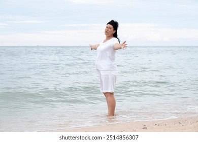 Happy mature woman with arms outstretched feeling the breeze at beach. Mid lady feeling good and enjoying freedom at sea, copy space - Powered by Shutterstock